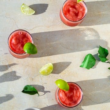 watermelon slushie in glass cup with mint, basil, lime