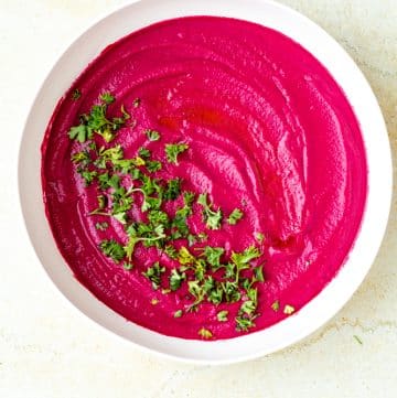 roasted beet hummus with chopped parsley and drizzled olive oil in bowl